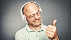 man listening to music on headphones, shows ok,